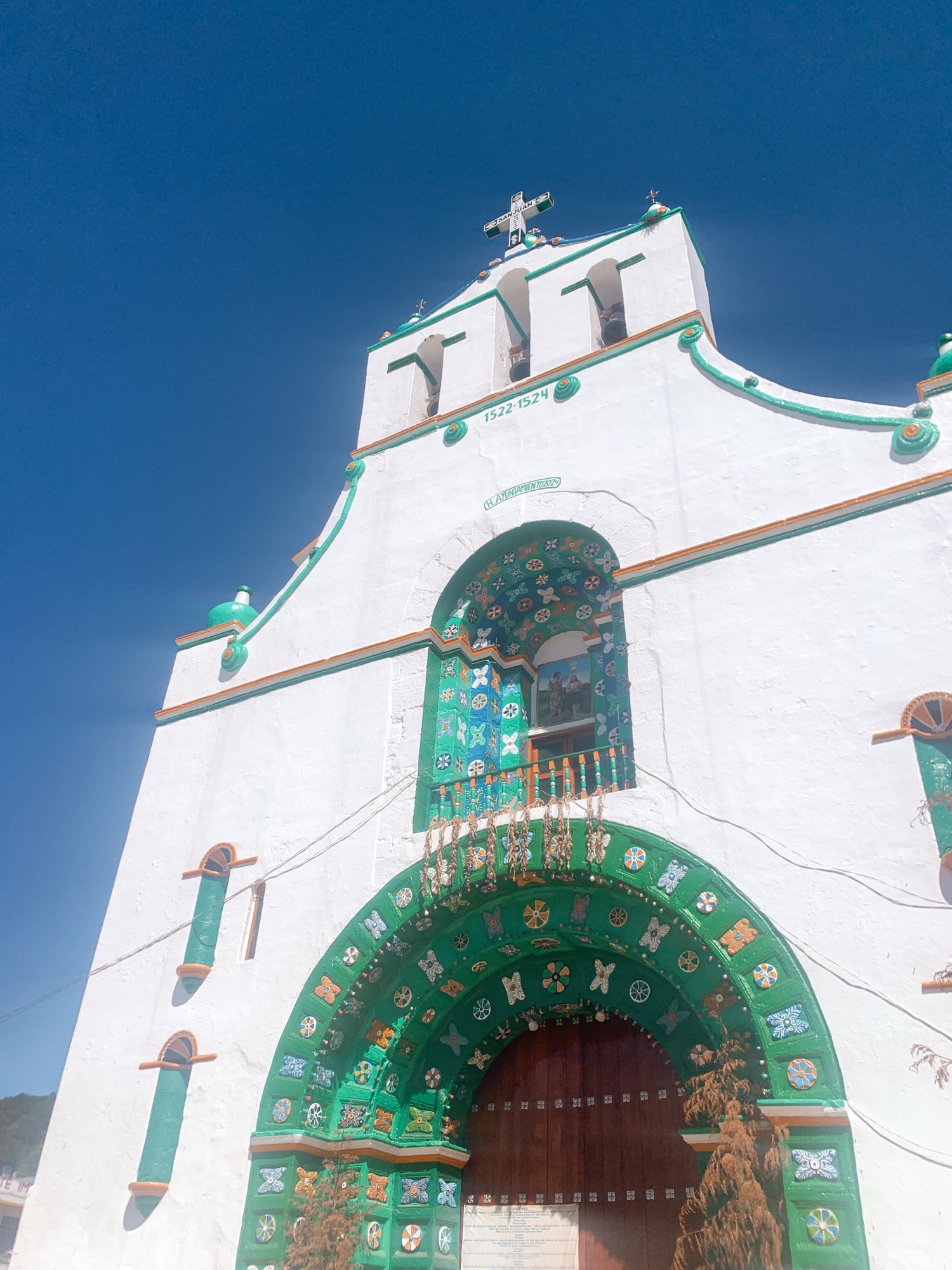 Photo of white church with green features and blue sky