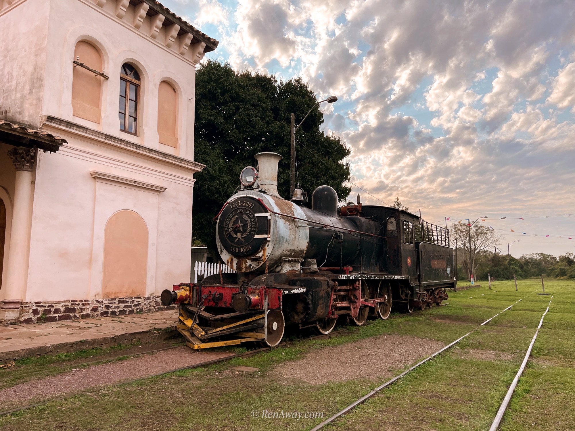 a vintage train sits out the front of a colonial building in pirayu, one of paraguay's picturesque towns between asuncion to encarnation